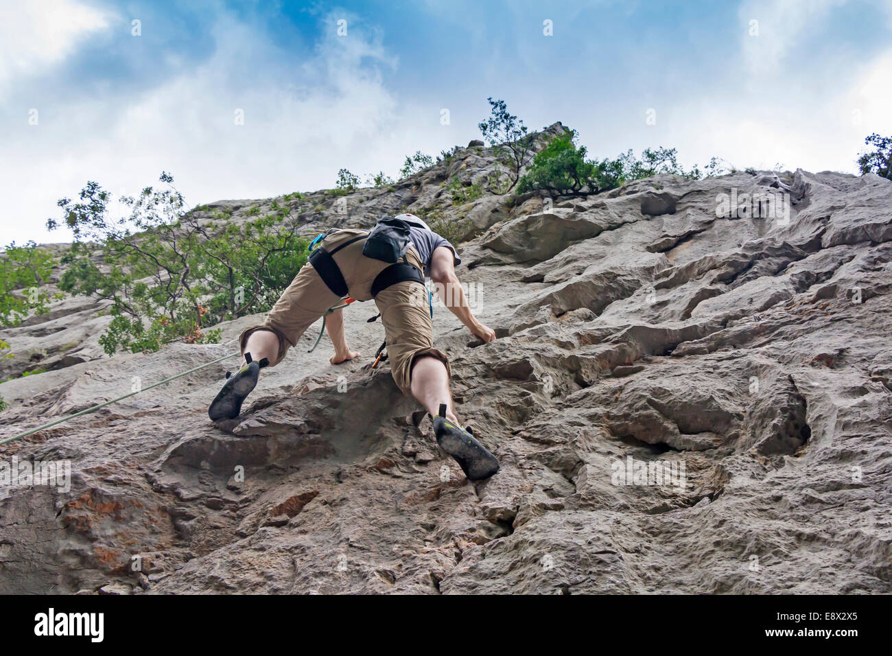 Athletic man rock climbing on a high rock wall Stock Photo