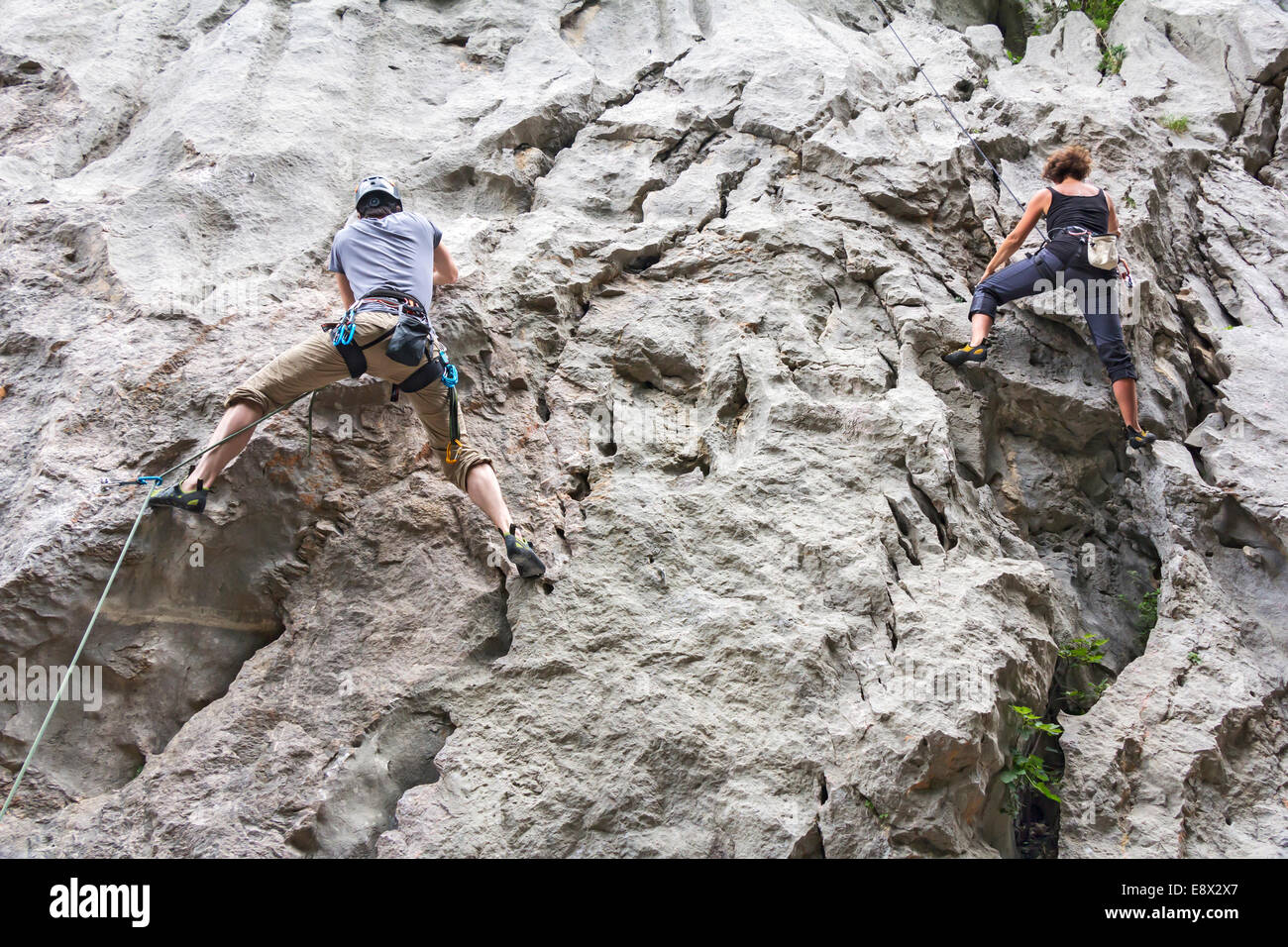 Woman and man rock climbing on a high rock wall Stock Photo