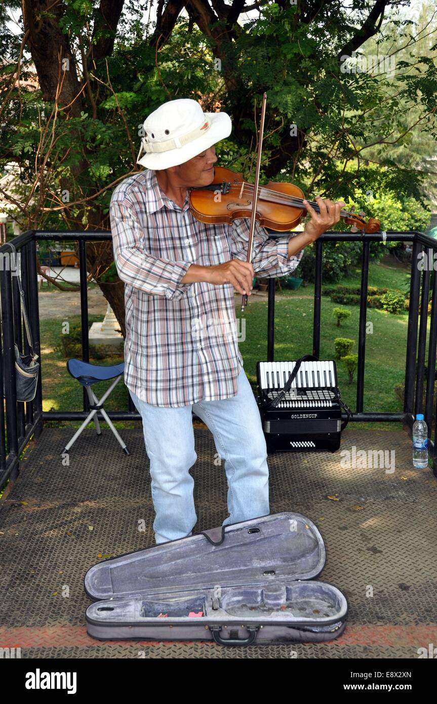 KANCHANABURI, THAILAND:  A violinist entertains tourists standing on the Bridge at the River Kwai hoping for contributions Stock Photo