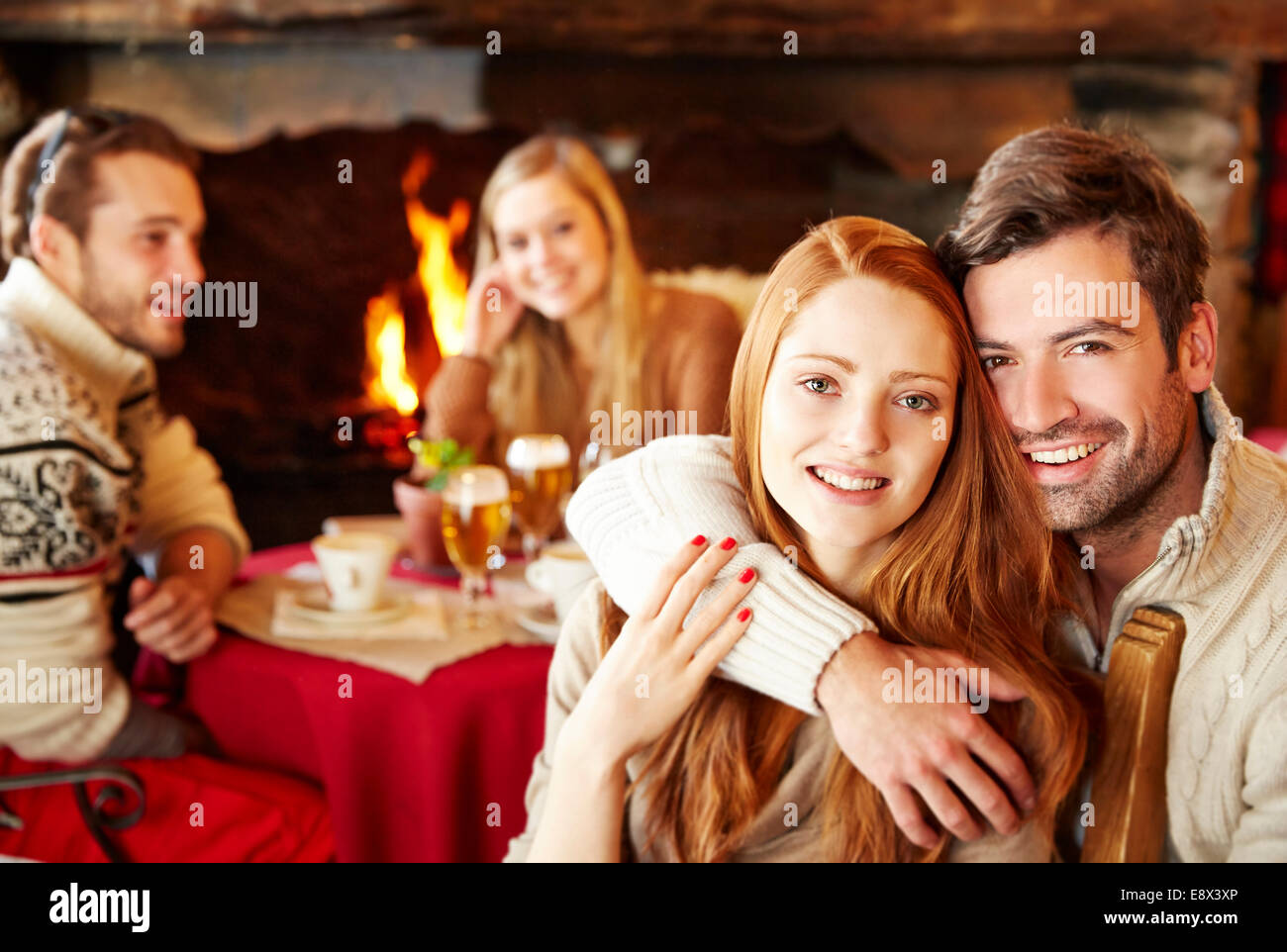 Couple hugging at restaurant with friends Stock Photo