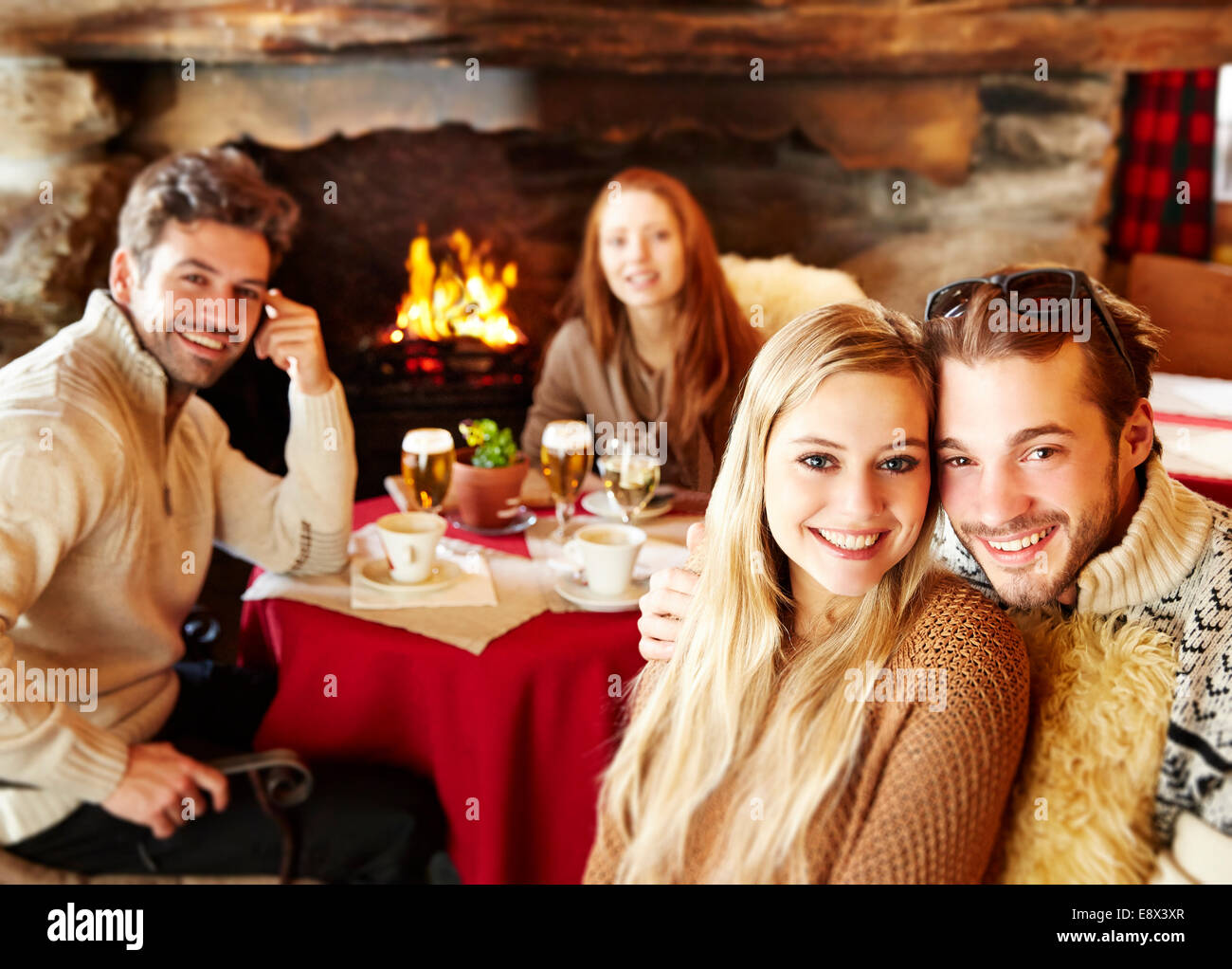 Friends eating together by fireplace Stock Photo