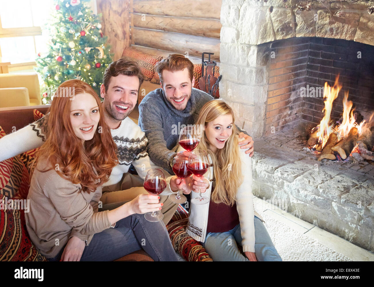 Friends celebrating with drinks in log cabin Stock Photo