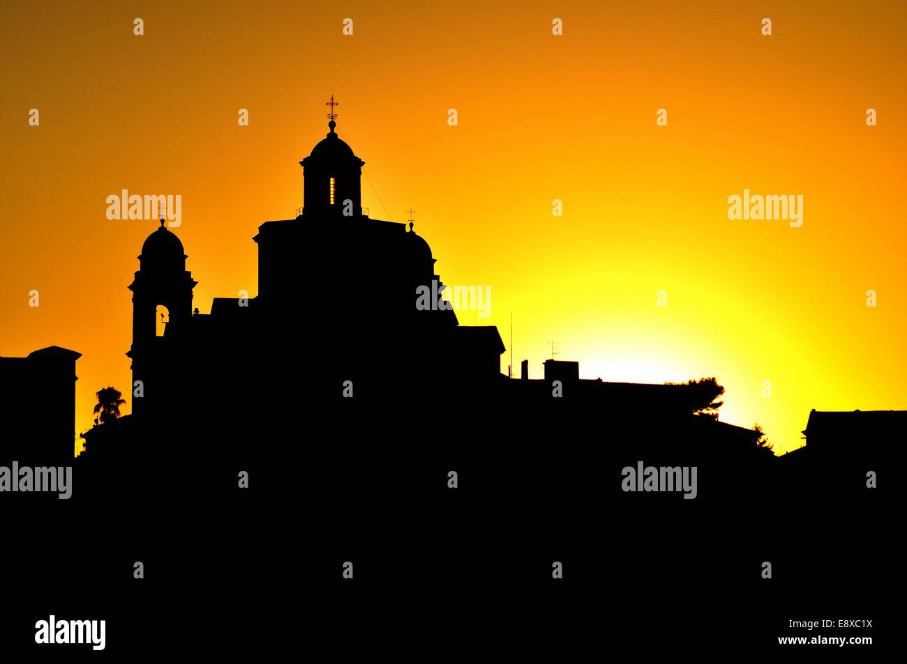 silhouetted town, church and clocktower, evening summer sunset in Imperia, Liguria, Italy Stock Photo