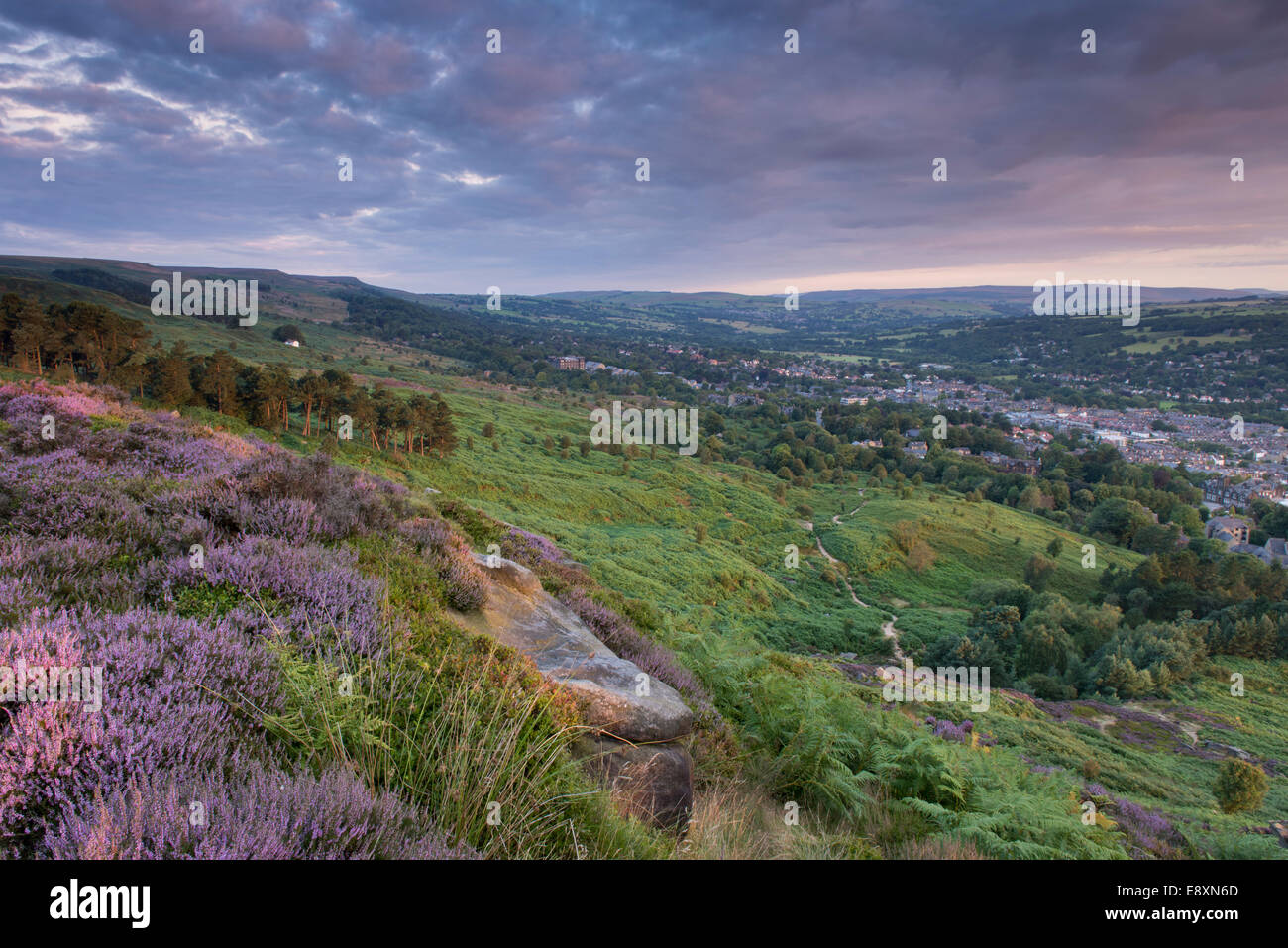 Under dramatic clouds, scenic rural morning sunrise view from high on Ilkley Moor, over town nestling in Wharfe Valley - West Yorkshire, England, UK. Stock Photo