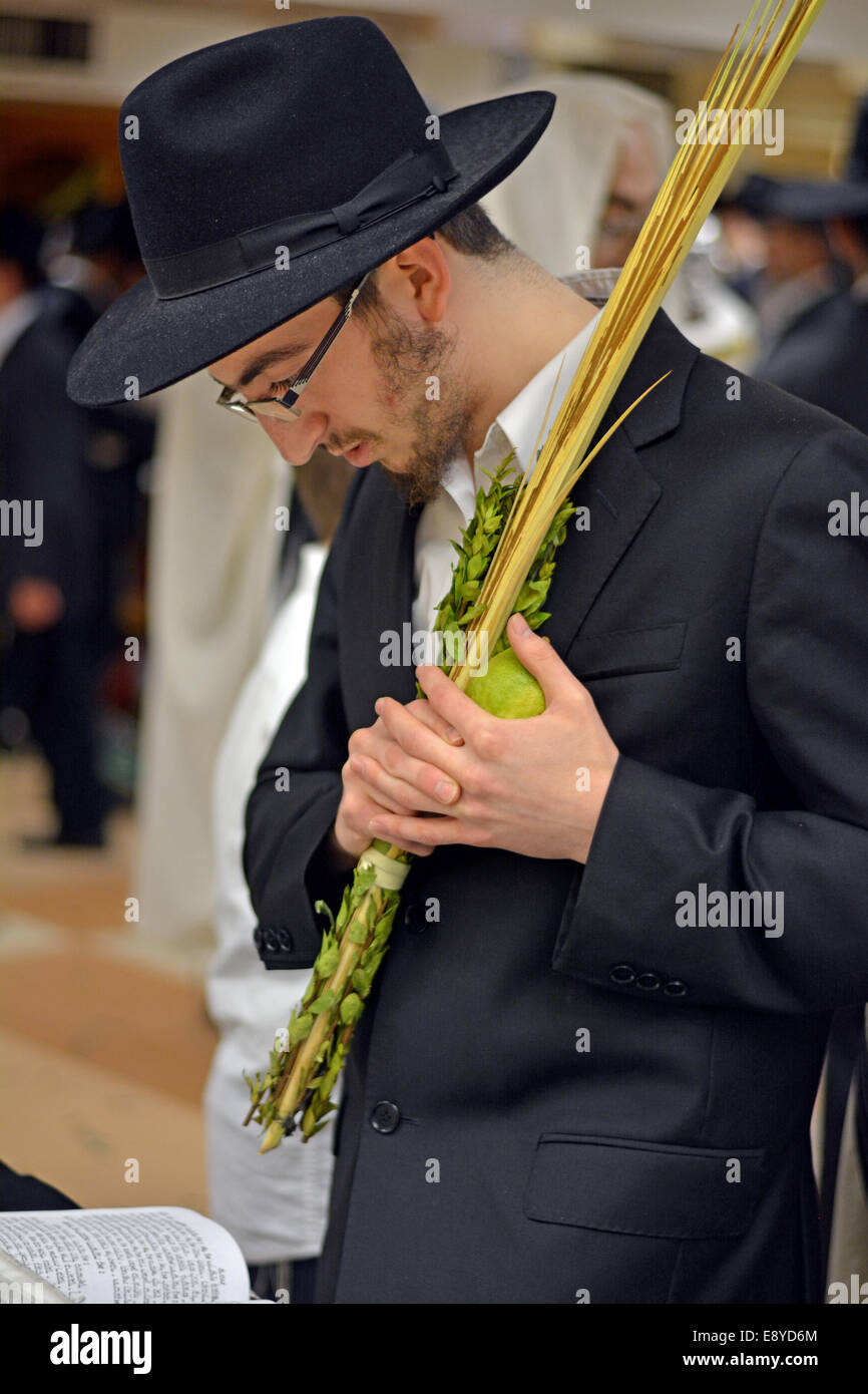 A religious Jewish young man holding an esrog and lulav at morning prayer services in Crown Heights, Brooklyn, New York Stock Photo