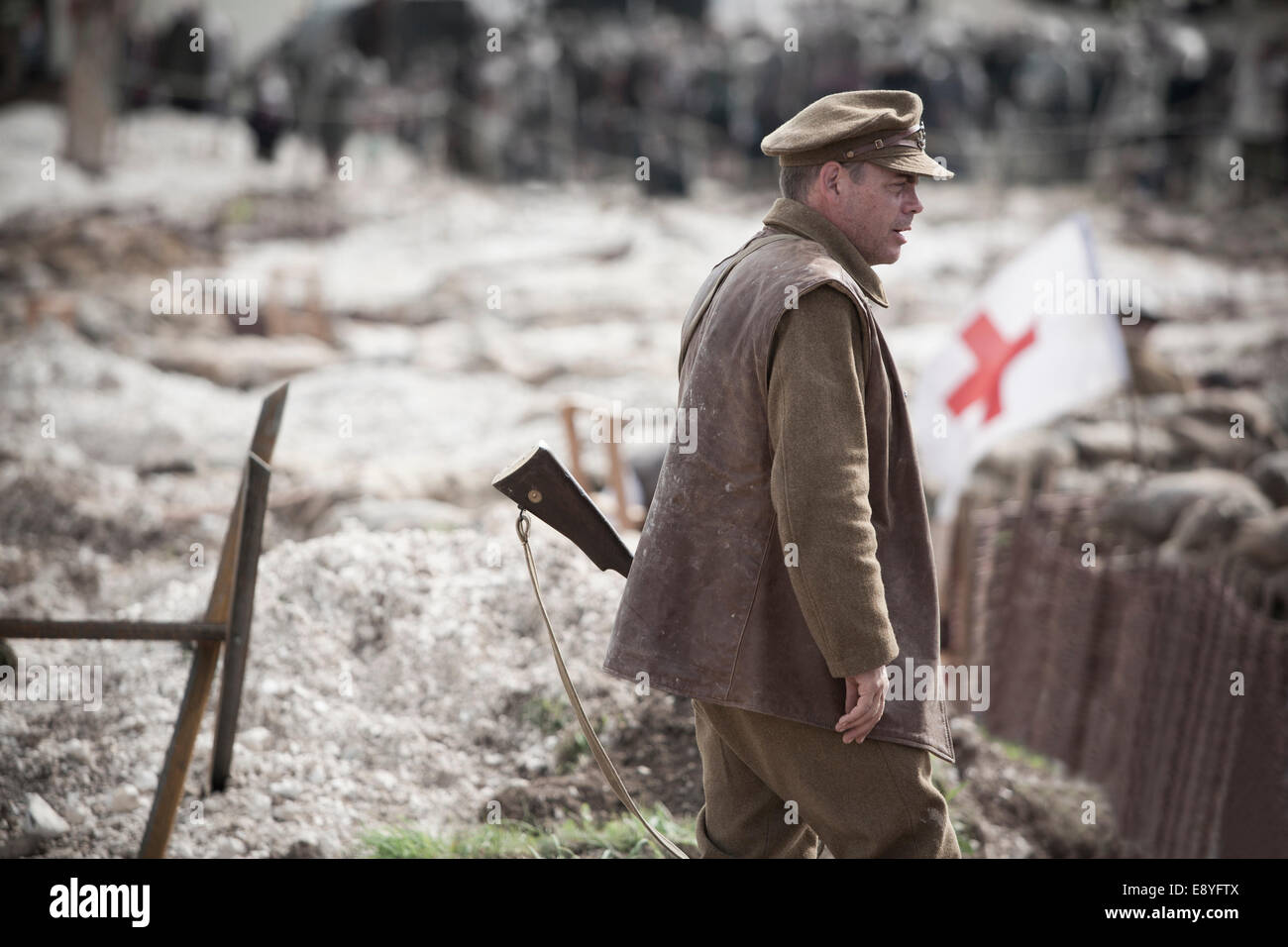 A man in WW1 British Army Soldier's uniform holding a rifle, stood by entrance to a trench. Stock Photo