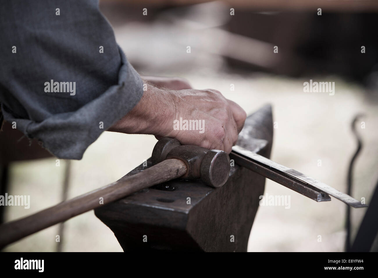 Close up view of blacksmiths hands working metal on an anvil. Stock Photo