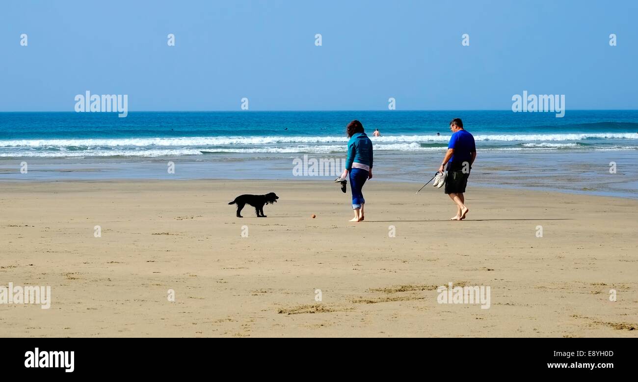 A couple with a black dog playing ball on Perranporth beach Cornwall England uk Stock Photo
