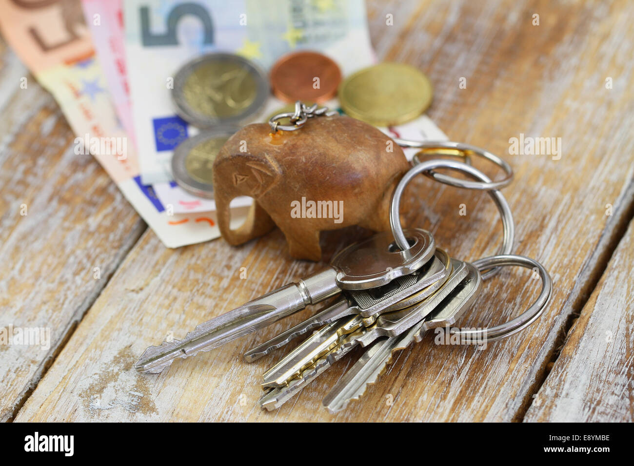 Bunch of keys on chain with little wooden elephant and banknotes Stock Photo