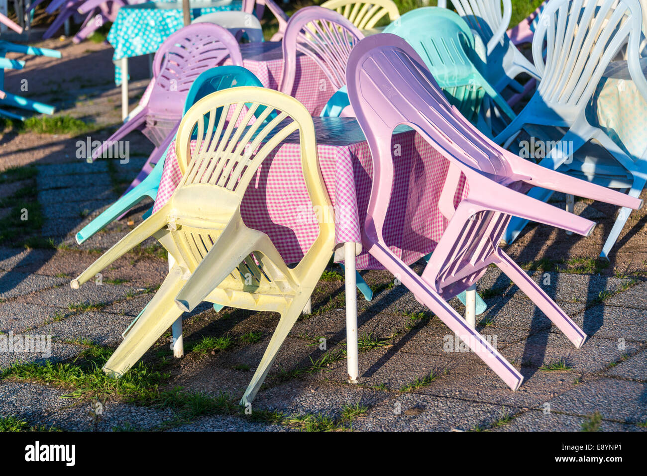 Colourful plastic chairs on the patio of a closed cafe Stock Photo