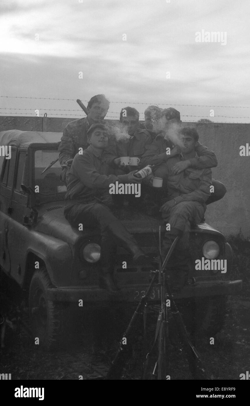 A group of soldiers with weapons near the army SUV UAZ-469. Film scan. Large grain Stock Photo