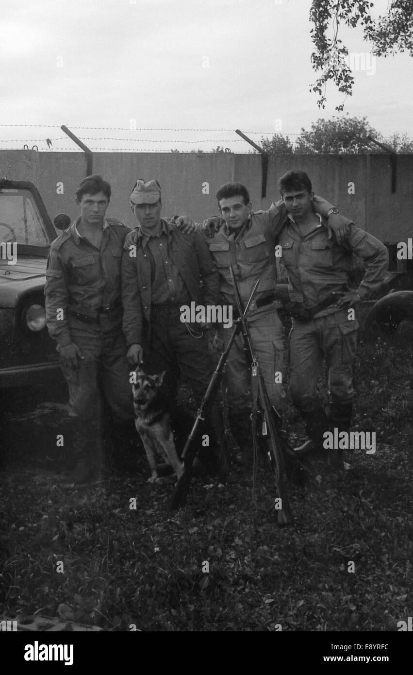 A group of soldiers with weapons near the army SUV UAZ-469. Film scan. Large grain Stock Photo