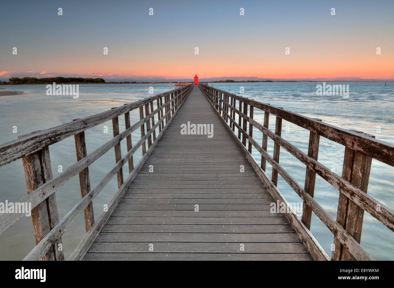 Wide angle shot of wooden pier with a red lighthouse Stock Photo