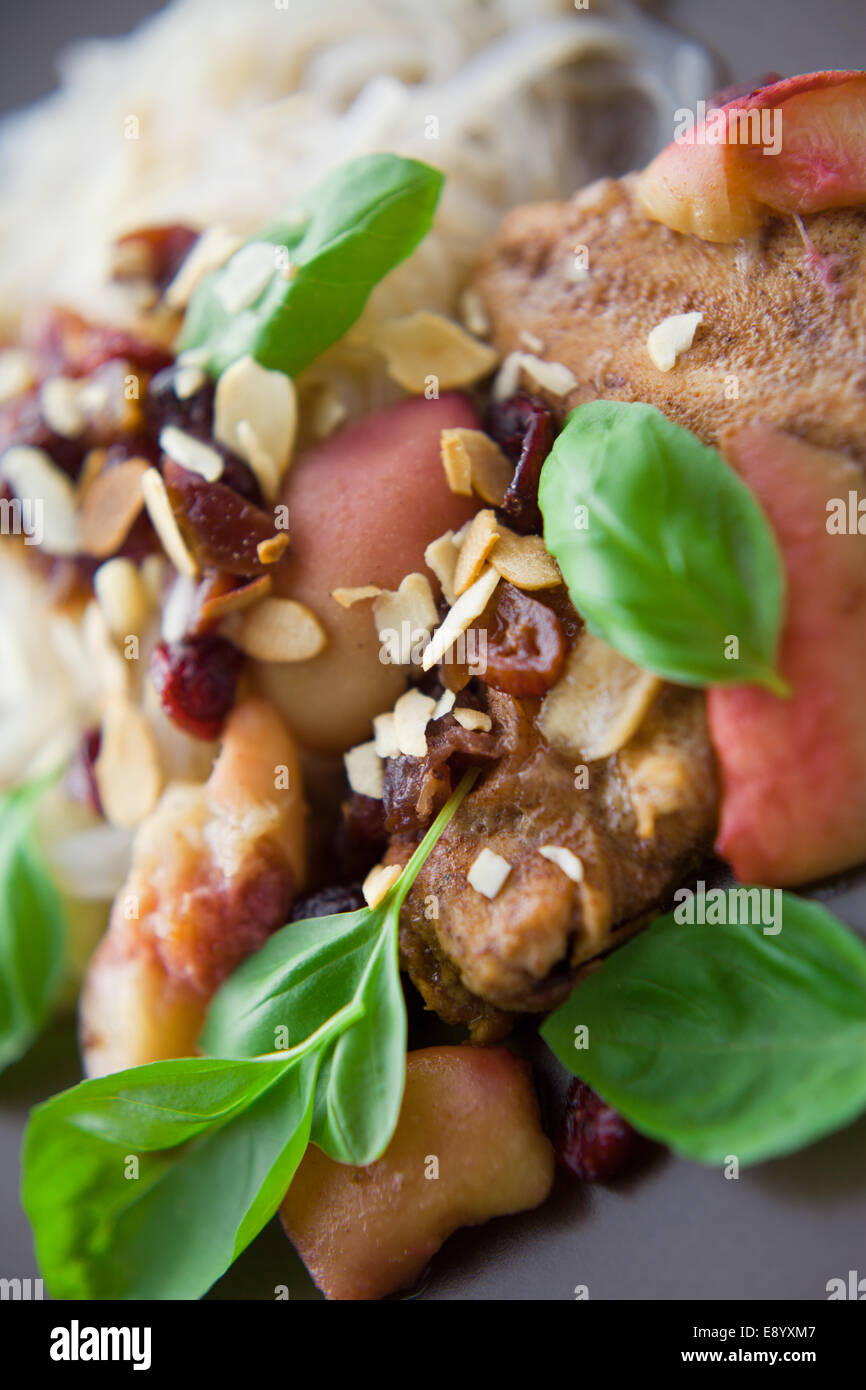 Fresh meal cooked with chicken, cranberries, almonds, and sweet peach fruits. All decorated with basil leaves. Stock Photo