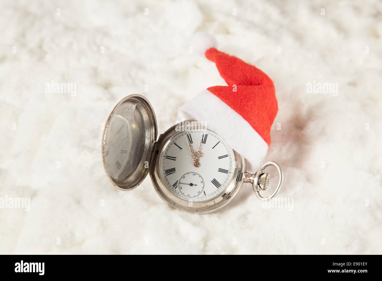 Old fashioned pocket watch with santa hat. On snow surface. Stock Photo