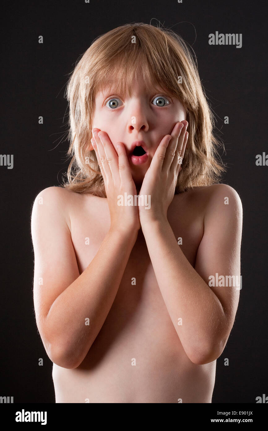 Boy with Blond Hair Surprised, Hands on his Cheeks Stock Photo
