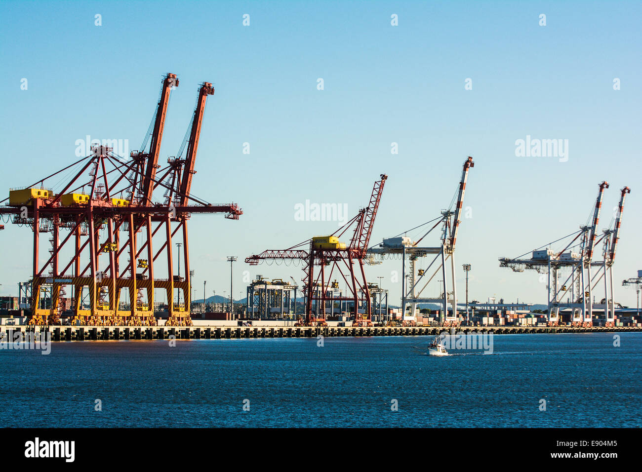 Boat sailing in front of container ship jetties, The Port of Brisbane, Brisbane, Queensland, Australia Stock Photo