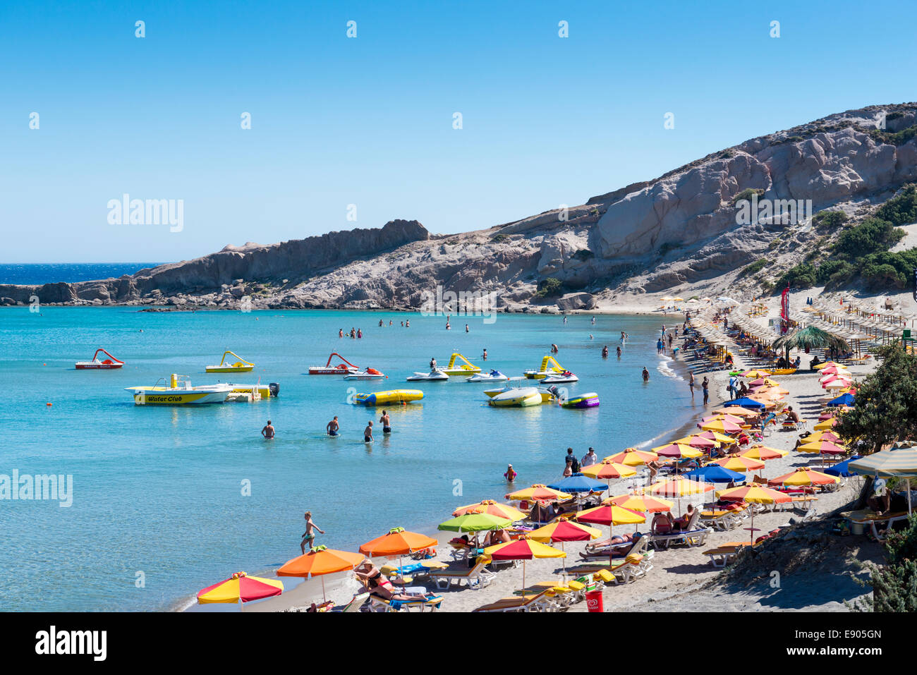 Parasols and boats at Paradise Beach at Kefalos Bay, island of Kos, Greece Stock Photo