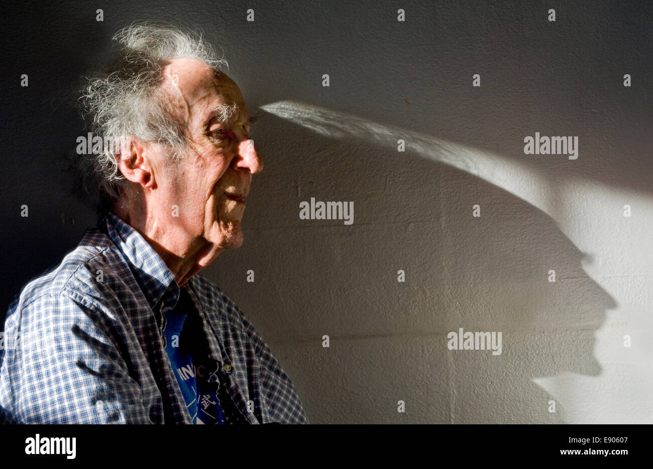 An elderly man casts a long shadow while listening to a music concert Stock Photo