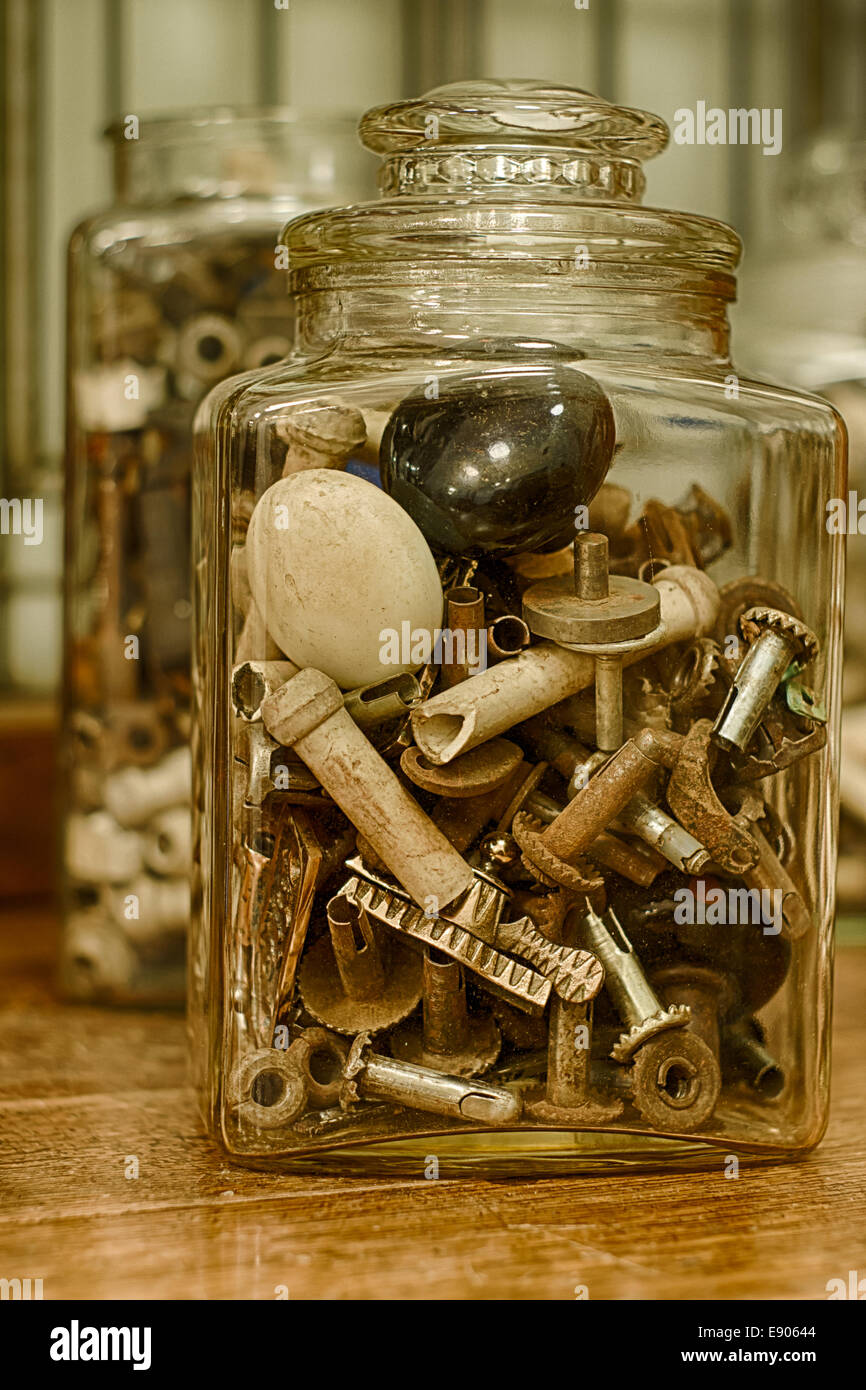 A glass jar filled with door knobs and other antique hardware salvage parts. Stock Photo