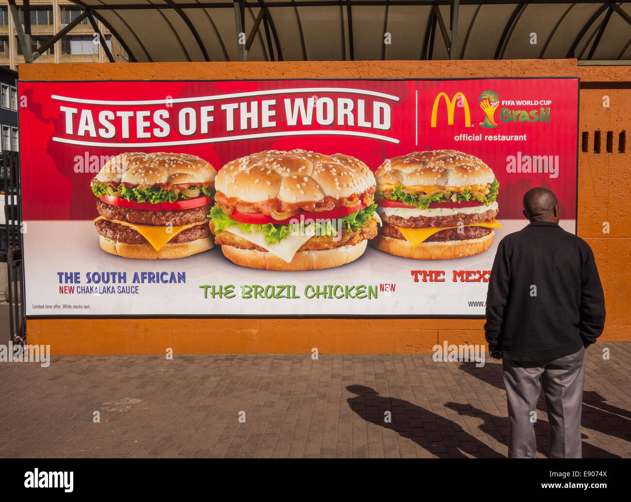 JOHANNESBURG, SOUTH AFRICA -McDonald's Restaurant billboard and man. Tastes of the World hamburger promotion. Stock Photo
