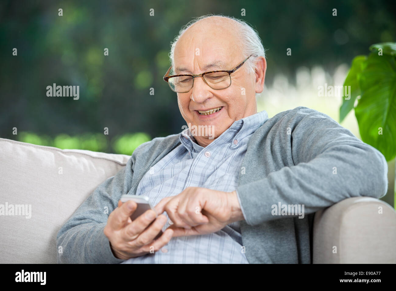 Smiling Senior Man Text Messaging Through Mobilephone Stock Photo