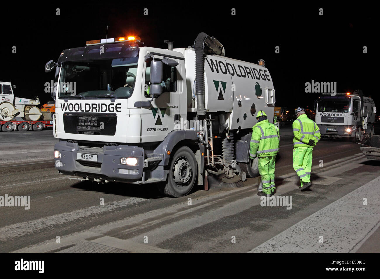 Maintenance teams resurface an airport runway during an overnight closure. A sweeping lorry removes debris prior to resurfacing Stock Photo