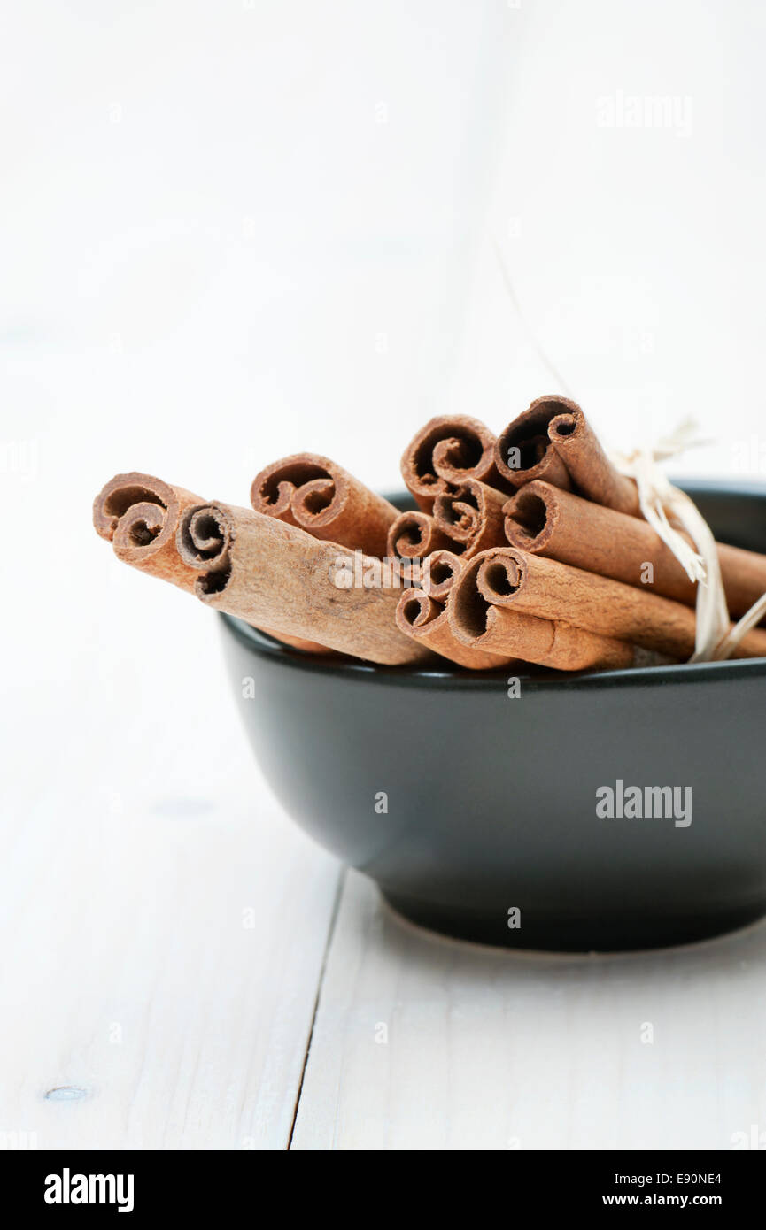 black cup with cinnamon sticks on wooden table Stock Photo