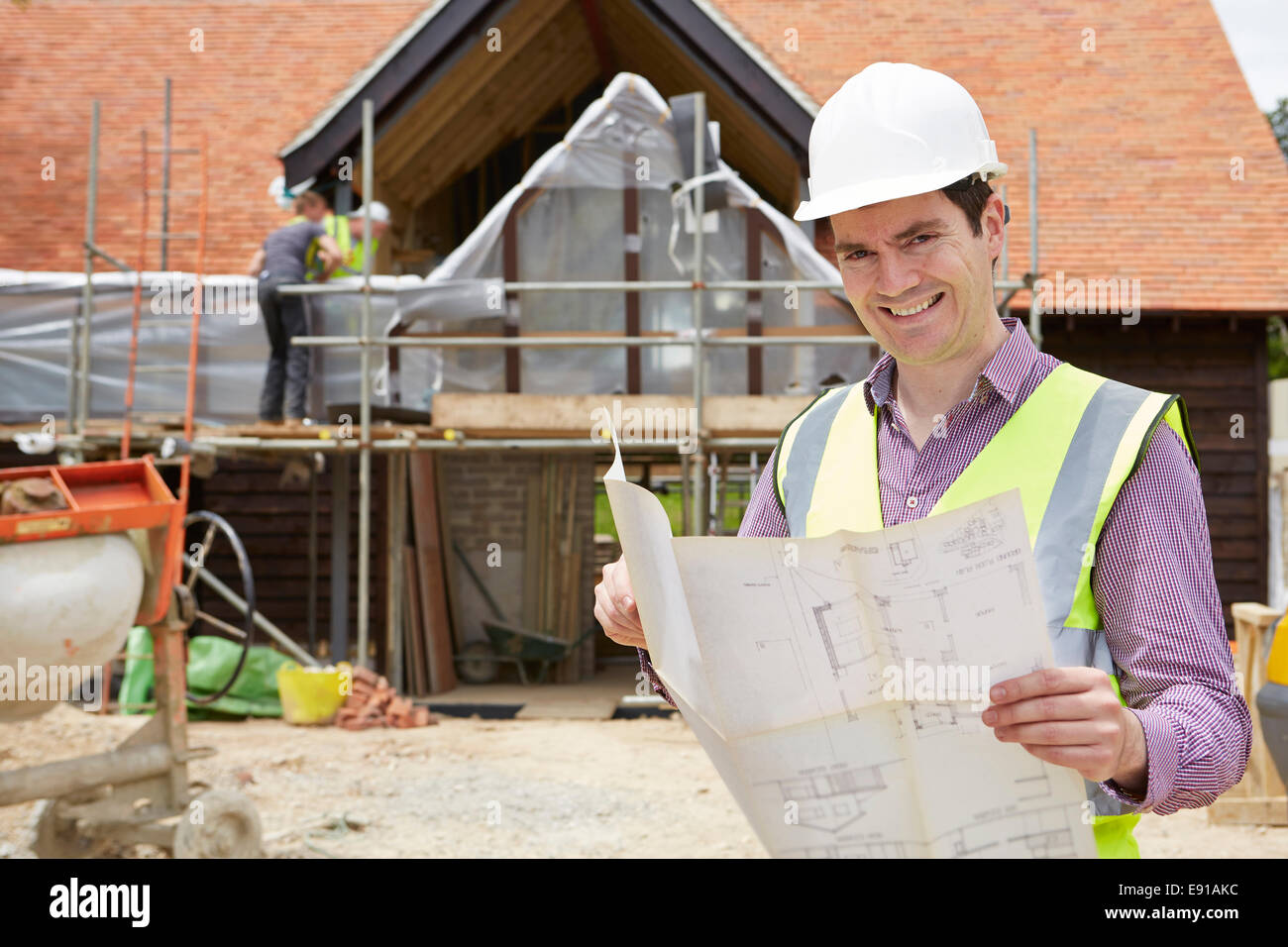 Architect On Building Site Looking At House Plans Stock Photo