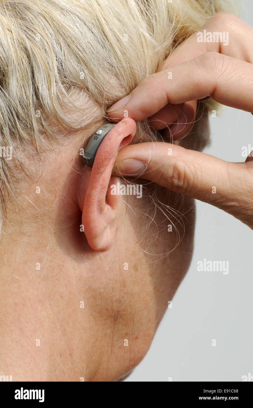 Modern small hearing aid behind the ear of a woman Stock Photo
