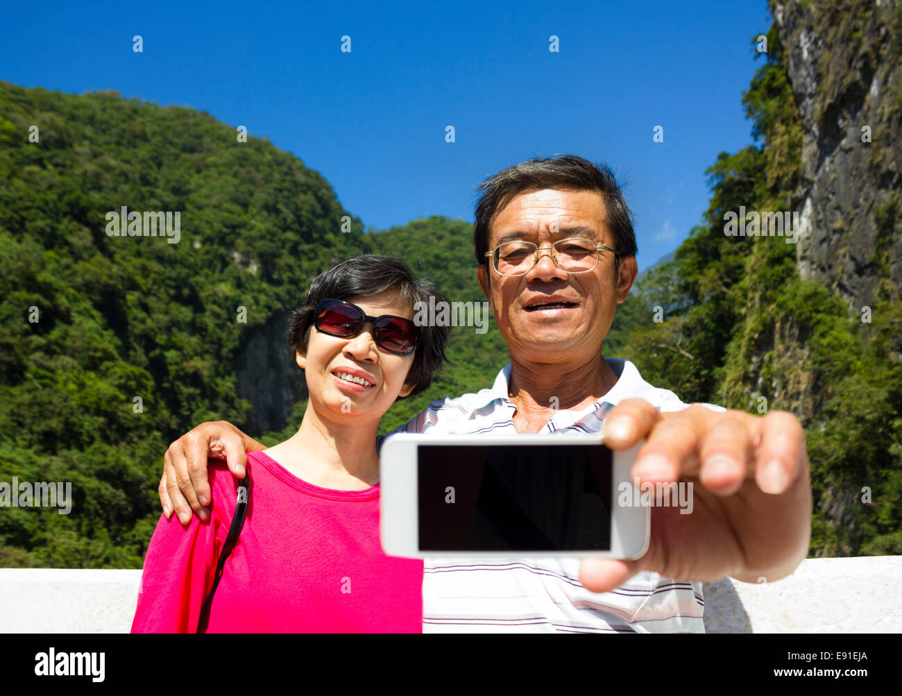 Senior couple taking picture of themselves outside with mountain background Stock Photo