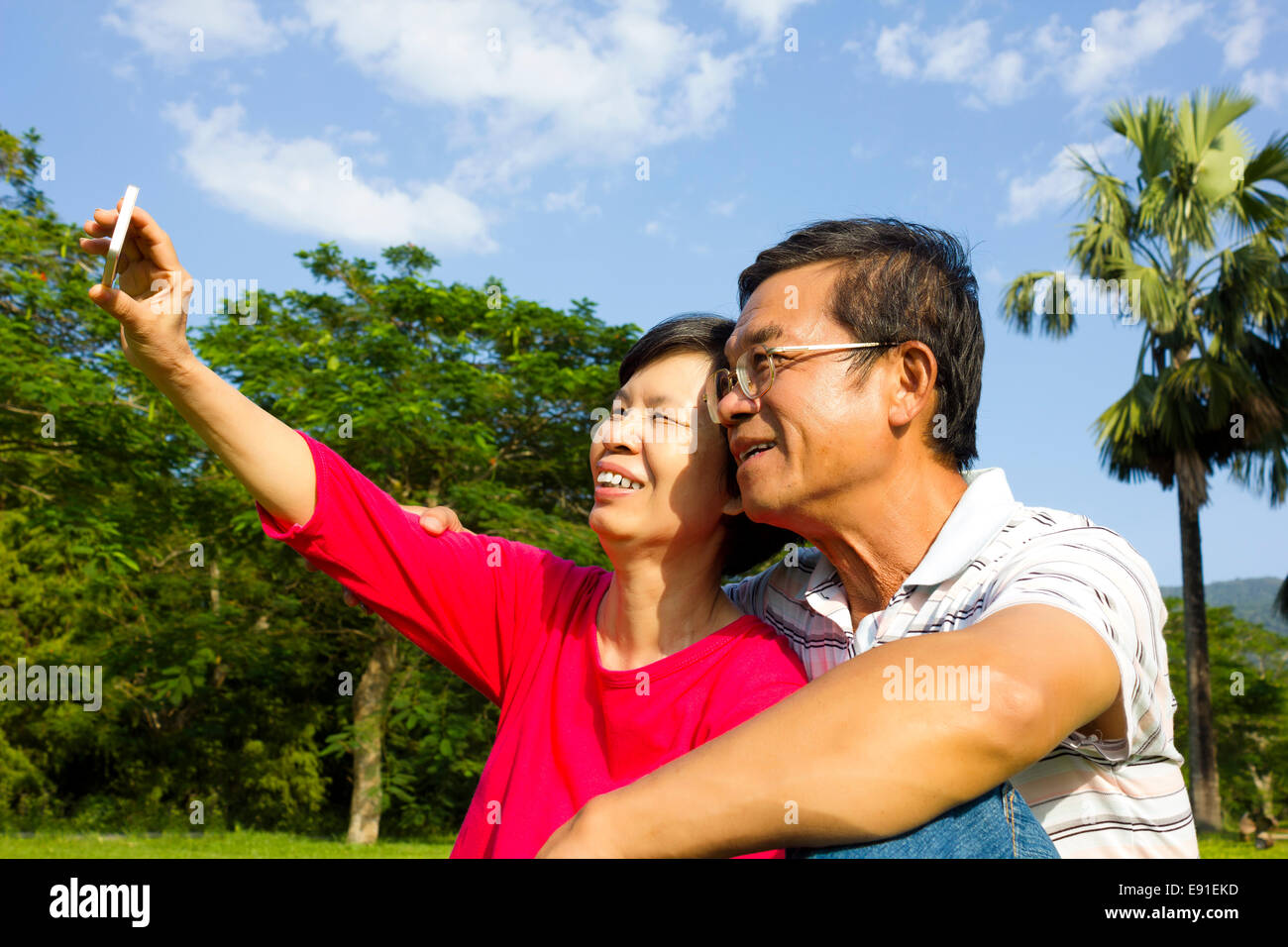 Senior couple sitting on grassland and  taking picture by themselves Stock Photo