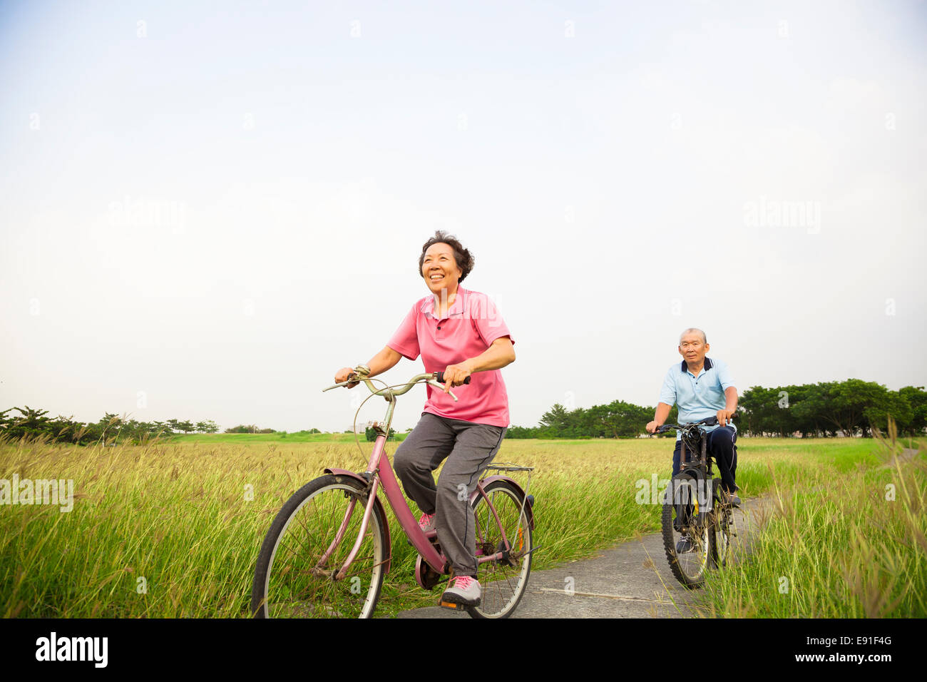 Happy Asian elderly seniors couple biking in the park Stock Photo