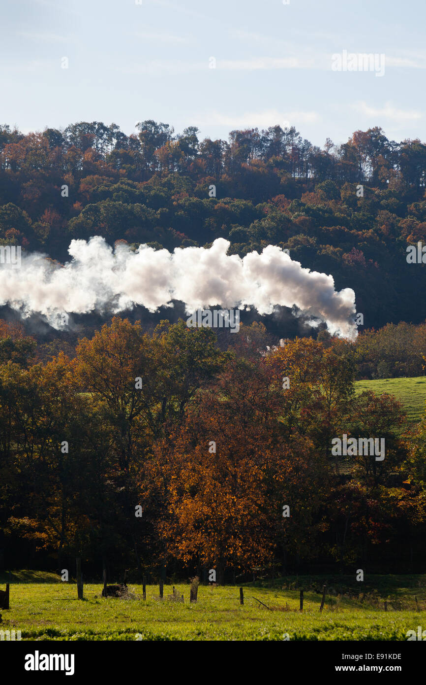 Steam train powers along railway Stock Photo