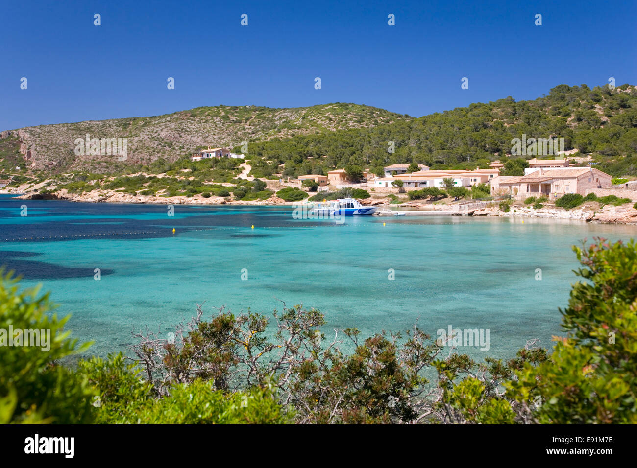 Island of Cabrera, Mallorca, Balearic Islands, Spain. View across bay to waterside houses, boat at quayside. Stock Photo