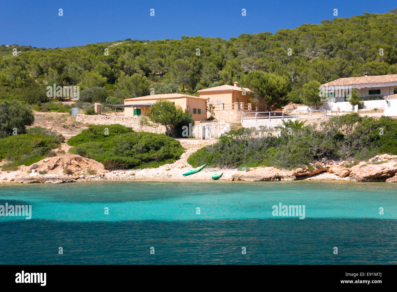 Island of Cabrera, Mallorca, Balearic Islands, Spain. View across bay to waterside houses, kayaks on shore. Stock Photo