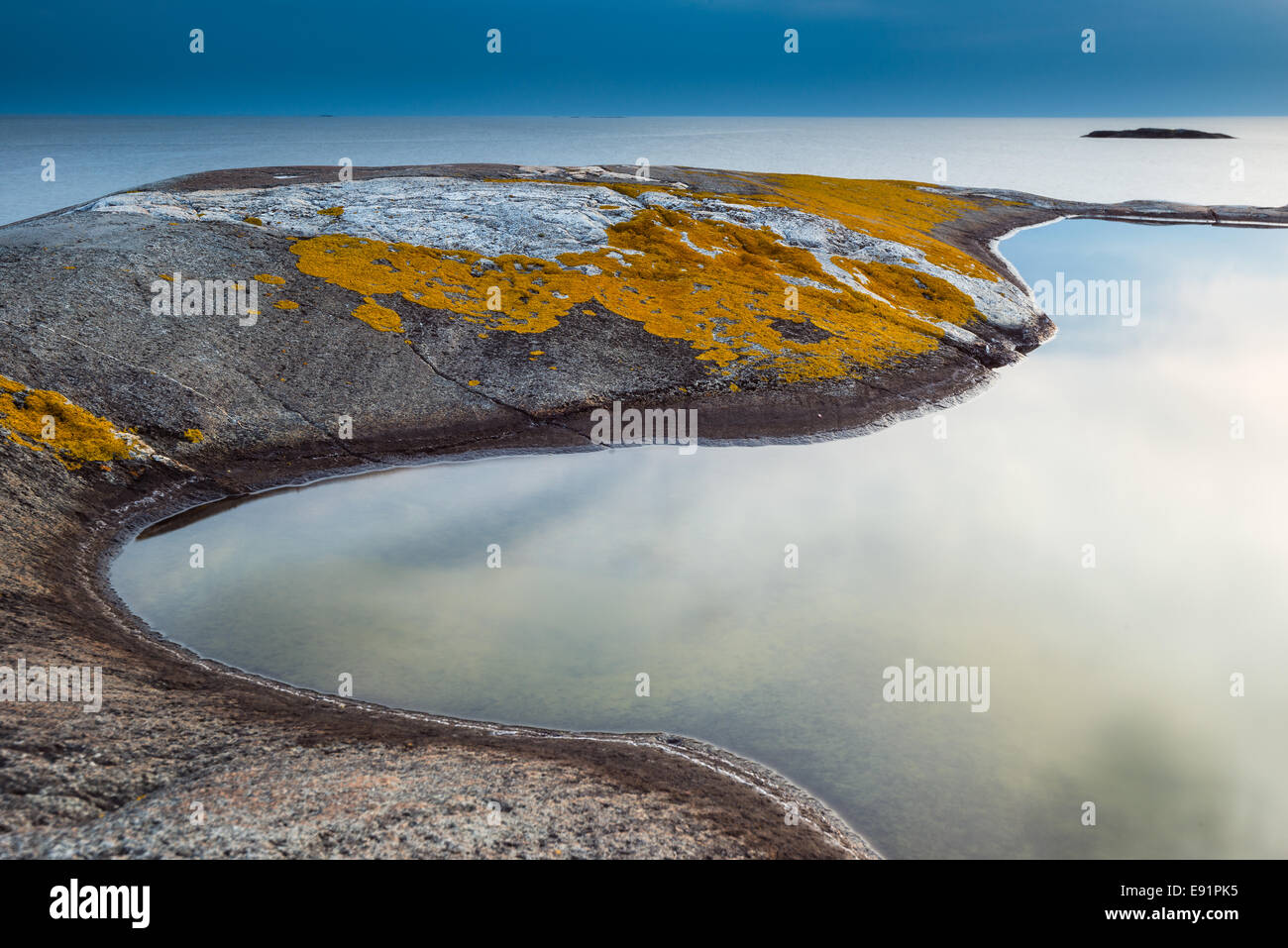 Smooth tide pool edged by mossy rock Stock Photo