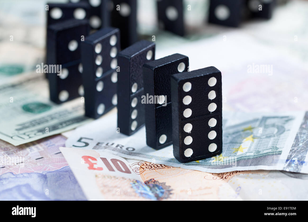 Standing dominoes on bank notes Stock Photo