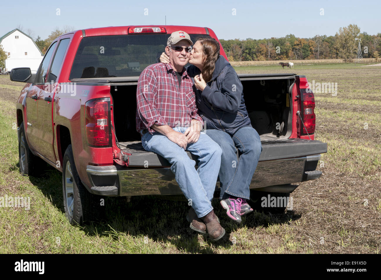 Mature Man And Woman Sitting On The Tailgate Of Their Truck She