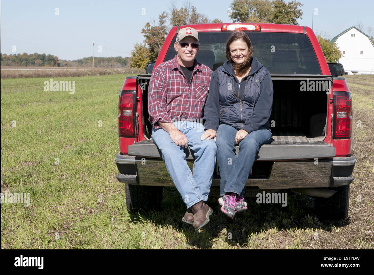 Mature couple sitting on tail gate of truck Stock Photo