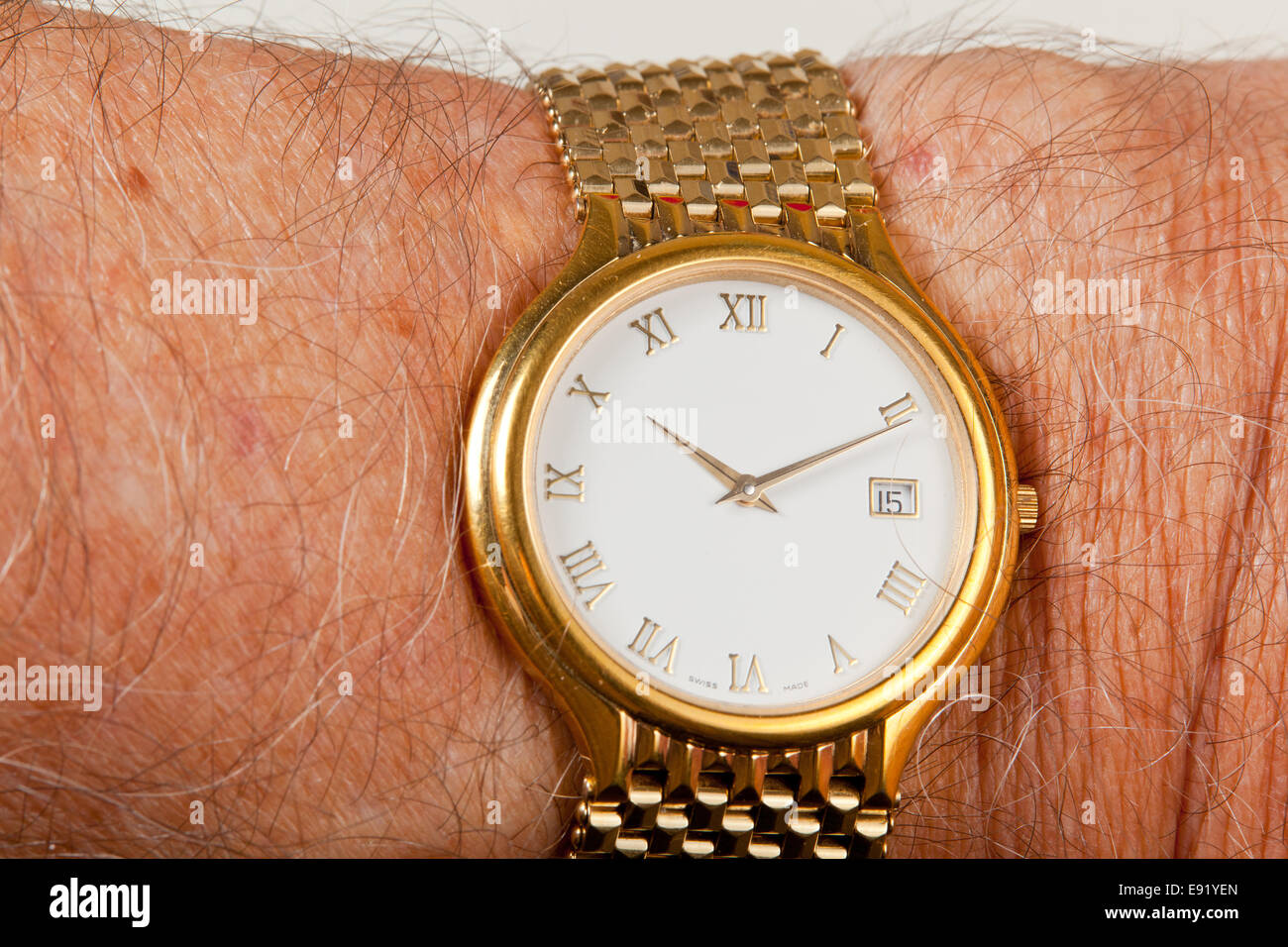 Gold watch with white face on hairy wrist Stock Photo