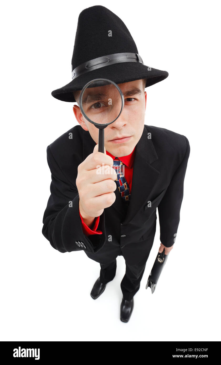 Young detective with briefcase, looking up through magnifying glass Stock Photo