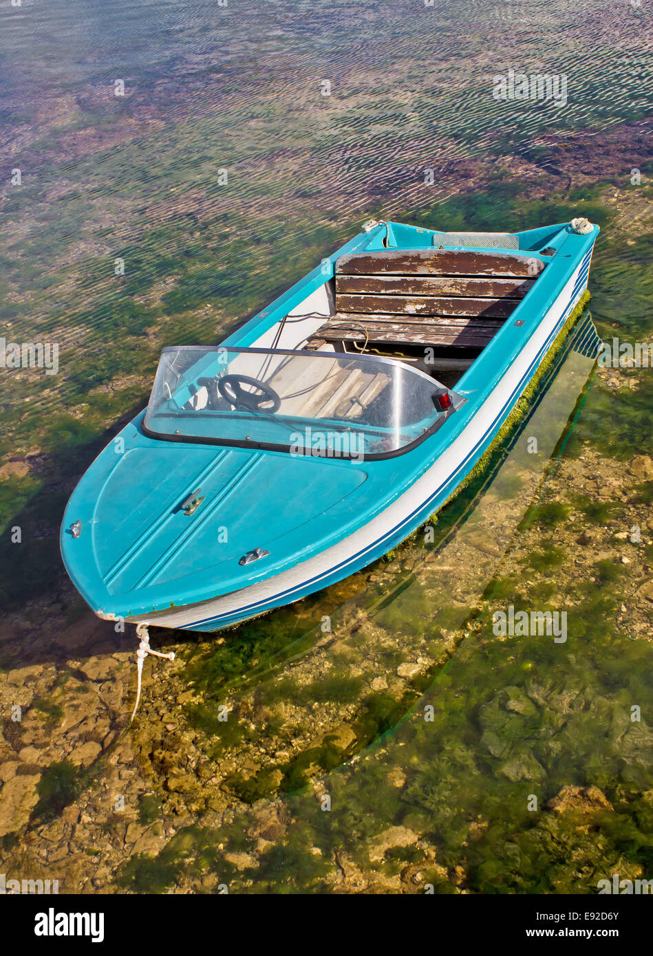Blue boat tied up in shallow sea Stock Photo