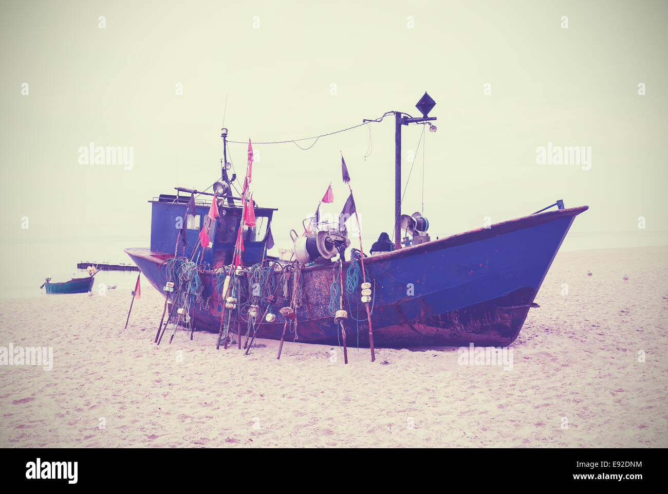 Small fishing boat on shore of the Baltic Sea, vintage retro style. Stock Photo