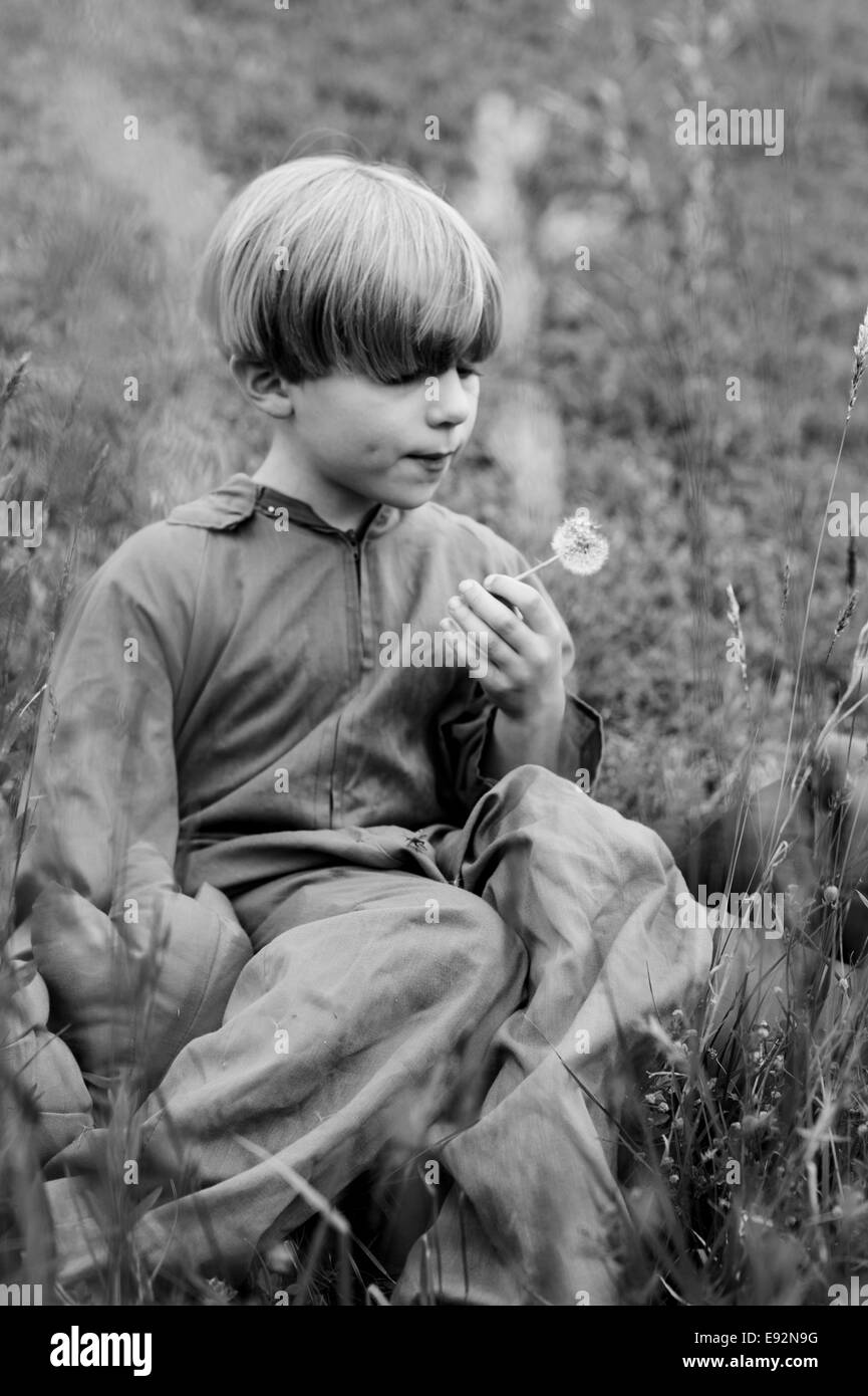 Boy in Costume Blowing Dandelion Stock Photo