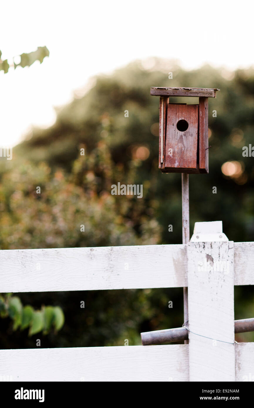 Red Birdhouse on White Fence Stock Photo
