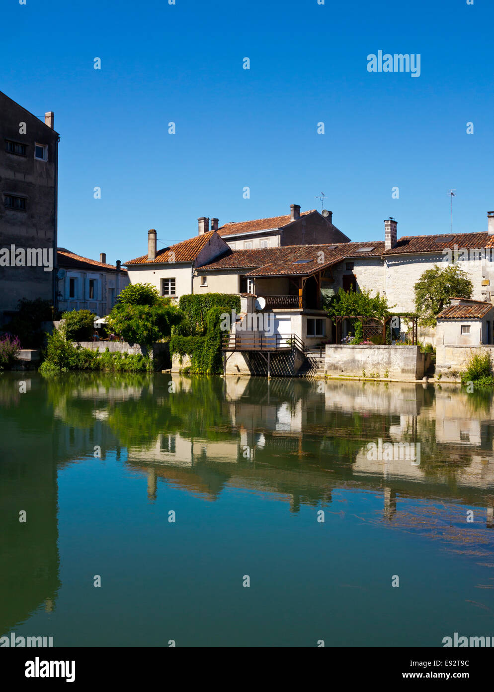 Buildings reflected in the River Charente flowing through Jarnac in the Charente Region of south west France Stock Photo