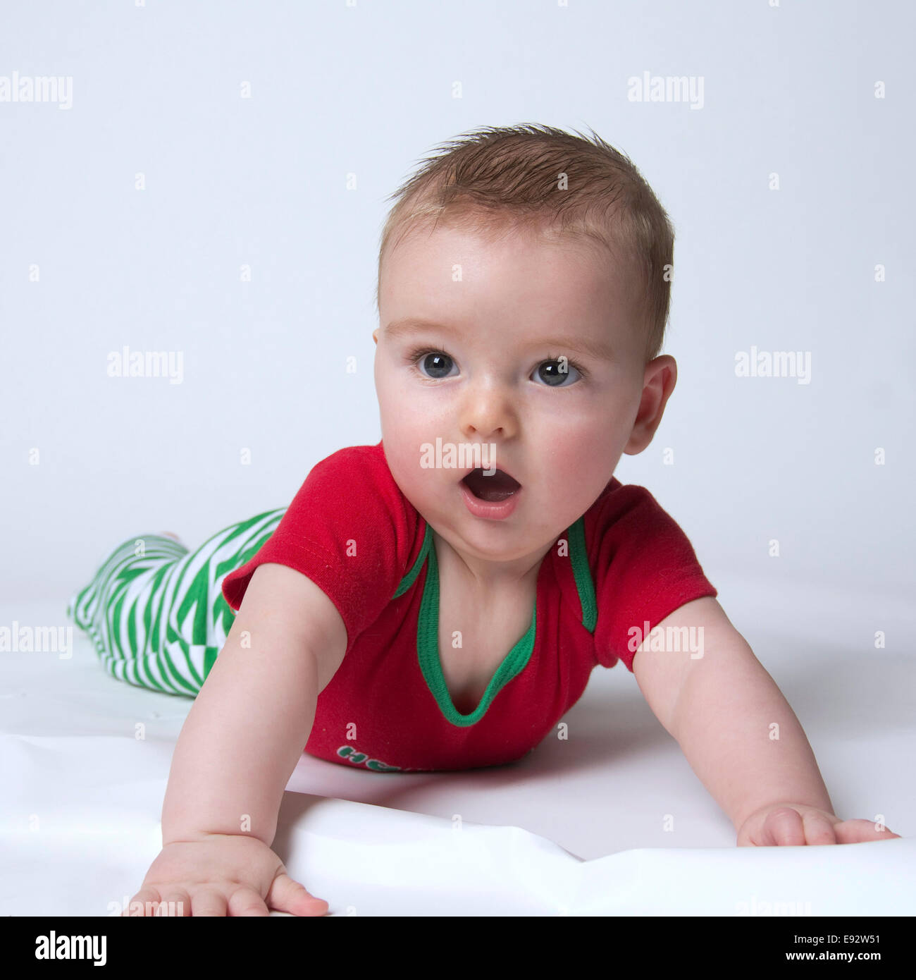 9 month old baby boy holding his head up wearing Christmas colors looking shocked and stunned Stock Photo