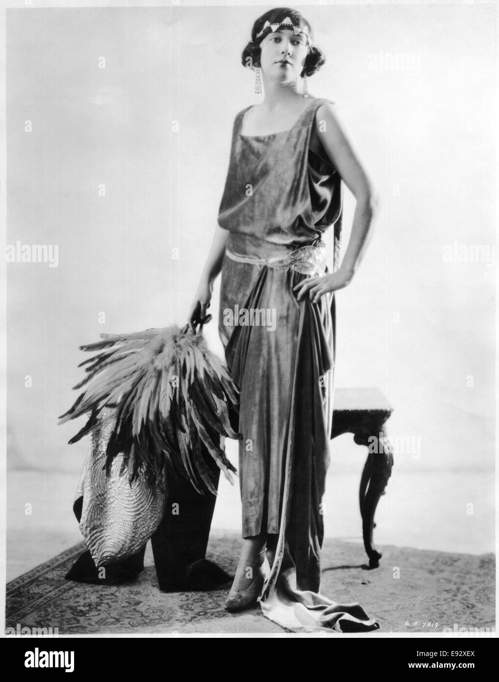 Fashionable Woman in Chiffon Velvet Dress Trimmed with Crystal and Headband Holding Feather Bouquet, Portrait, circa 1922 Stock Photo