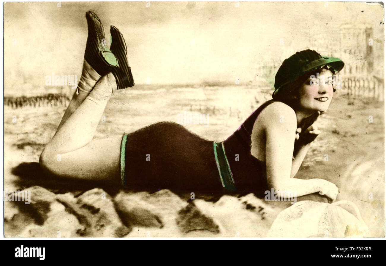 Smiling Woman in One-Piece Swimsuit and Cap Laying on Ground with Hand under Chin, Portrait, Postcard, circa early 1900's Stock Photo